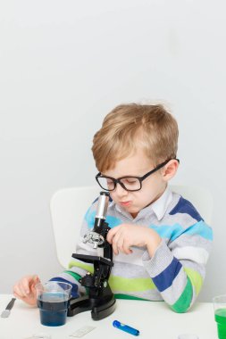 Çocuk beş yaşında, renkli sıvılarla deney yapıyor. Avrupa görünümlü küçük bir bilim adamının kimyasal deneyleri..