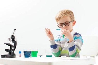 Çocuk beş yaşında, renkli sıvılarla deney yapıyor. Avrupa görünümlü küçük bir bilim adamının kimyasal deneyleri..
