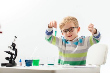 Çocuk beş yaşında, renkli sıvılarla deney yapıyor. Avrupa görünümlü küçük bir bilim adamının kimyasal deneyleri..