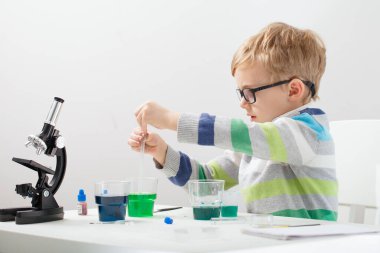 Çocuk beş yaşında, renkli sıvılarla deney yapıyor. Avrupa görünümlü küçük bir bilim adamının kimyasal deneyleri..
