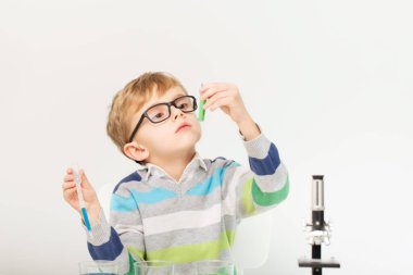 Çocuk beş yaşında, renkli sıvılarla deney yapıyor. Avrupa görünümlü küçük bir bilim adamının kimyasal deneyleri..