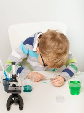 Çocuk beş yaşında, renkli sıvılarla deney yapıyor. Avrupa görünümlü küçük bir bilim adamının kimyasal deneyleri..