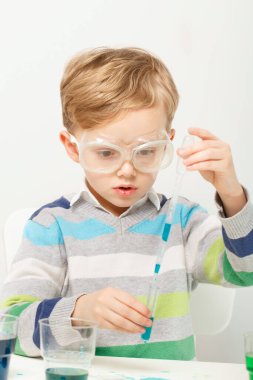 Çocuk beş yaşında, renkli sıvılarla deney yapıyor. Avrupa görünümlü küçük bir bilim adamının kimyasal deneyleri..