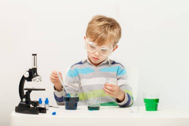 Çocuk beş yaşında, renkli sıvılarla deney yapıyor. Avrupa görünümlü küçük bir bilim adamının kimyasal deneyleri..