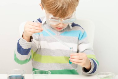 Çocuk beş yaşında, renkli sıvılarla deney yapıyor. Avrupa görünümlü küçük bir bilim adamının kimyasal deneyleri..