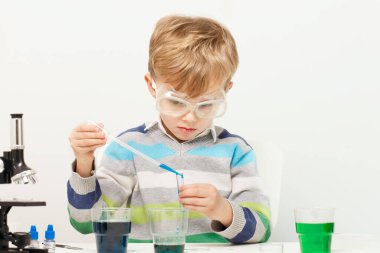 Çocuk beş yaşında, renkli sıvılarla deney yapıyor. Avrupa görünümlü küçük bir bilim adamının kimyasal deneyleri..