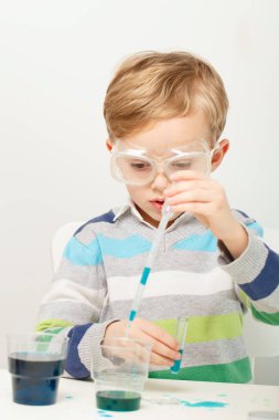 Çocuk beş yaşında, renkli sıvılarla deney yapıyor. Avrupa görünümlü küçük bir bilim adamının kimyasal deneyleri..
