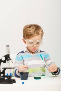 Çocuk beş yaşında, renkli sıvılarla deney yapıyor. Avrupa görünümlü küçük bir bilim adamının kimyasal deneyleri..