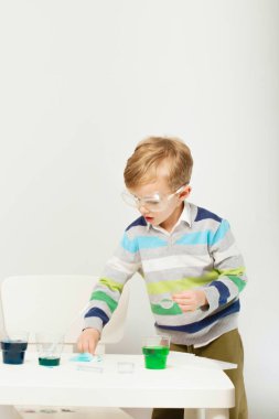 Çocuk beş yaşında, renkli sıvılarla deney yapıyor. Avrupa görünümlü küçük bir bilim adamının kimyasal deneyleri..