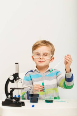 Çocuk beş yaşında, renkli sıvılarla deney yapıyor. Avrupa görünümlü küçük bir bilim adamının kimyasal deneyleri..