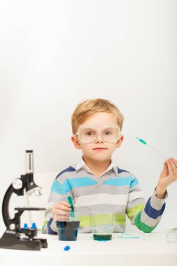 Çocuk beş yaşında, renkli sıvılarla deney yapıyor. Avrupa görünümlü küçük bir bilim adamının kimyasal deneyleri..