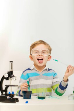 Çocuk beş yaşında, renkli sıvılarla deney yapıyor. Avrupa görünümlü küçük bir bilim adamının kimyasal deneyleri..