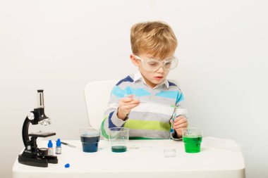 Çocuk beş yaşında, renkli sıvılarla deney yapıyor. Avrupa görünümlü küçük bir bilim adamının kimyasal deneyleri..