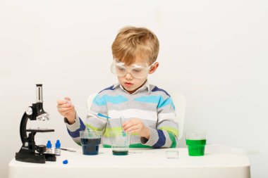 Çocuk beş yaşında, renkli sıvılarla deney yapıyor. Avrupa görünümlü küçük bir bilim adamının kimyasal deneyleri..