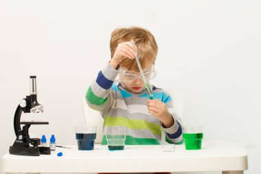 Çocuk beş yaşında, renkli sıvılarla deney yapıyor. Avrupa görünümlü küçük bir bilim adamının kimyasal deneyleri..