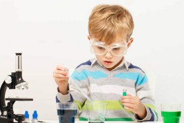 Çocuk beş yaşında, renkli sıvılarla deney yapıyor. Avrupa görünümlü küçük bir bilim adamının kimyasal deneyleri..