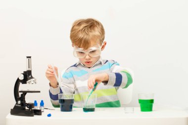 Çocuk beş yaşında, renkli sıvılarla deney yapıyor. Avrupa görünümlü küçük bir bilim adamının kimyasal deneyleri..