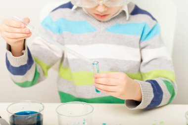 Çocuk beş yaşında, renkli sıvılarla deney yapıyor. Avrupa görünümlü küçük bir bilim adamının kimyasal deneyleri..
