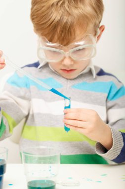 Çocuk beş yaşında, renkli sıvılarla deney yapıyor. Avrupa görünümlü küçük bir bilim adamının kimyasal deneyleri..