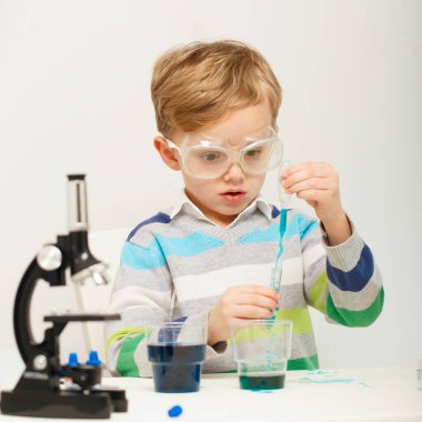 Çocuk beş yaşında, renkli sıvılarla deney yapıyor. Avrupa görünümlü küçük bir bilim adamının kimyasal deneyleri..