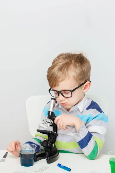 Çocuk beş yaşında, renkli sıvılarla deney yapıyor. Avrupa görünümlü küçük bir bilim adamının kimyasal deneyleri..