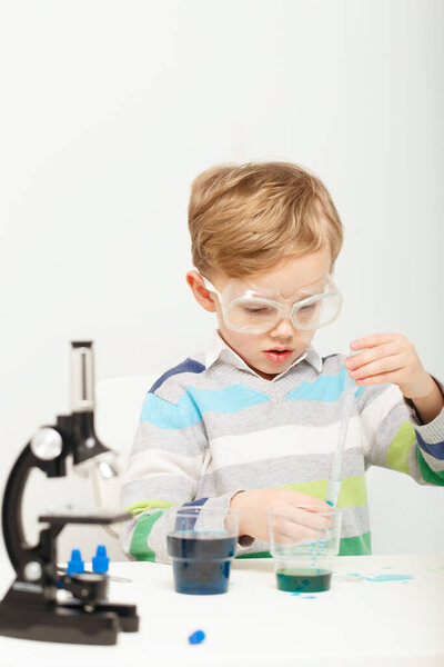 Boy five years old, experimenting with colored liquids. Chemical experiments of a little scientist boy of European appearance.