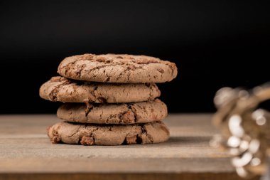 Kahverengi çikolatalı kurabiye büyük poan. Siyah bir arka planda. Kahverengi çikolata parçalı çikolatalı kurabiyeler ahşap bir masaya konur..