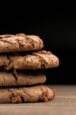 Kahverengi çikolatalı kurabiye büyük poan. Siyah bir arka planda. Kahverengi çikolata parçalı çikolatalı kurabiyeler ahşap bir masaya konur..