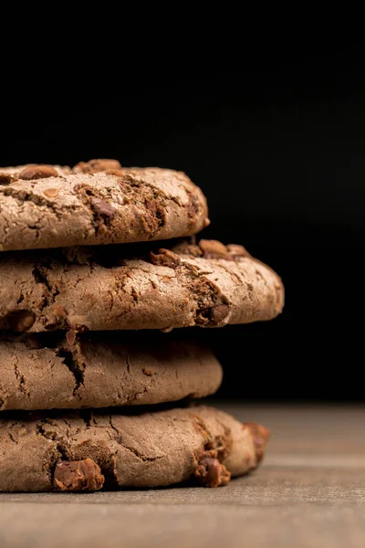 Kahverengi çikolatalı kurabiye büyük poan. Siyah bir arka planda. Kahverengi çikolata parçalı çikolatalı kurabiyeler ahşap bir masaya konur..