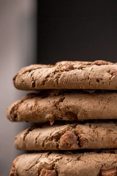 Kahverengi çikolatalı kurabiye büyük poan. Siyah bir arka planda. Kahverengi çikolata parçalı çikolatalı kurabiyeler ahşap bir masaya konur..