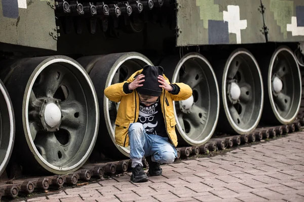 Ukrayna 'da savaş, patlamalardan saklanan çocuk. Tank ve obüs Ukrayna' da sokakta duruyor. Kiev parkında bir silah ve yeşil bir tank var..