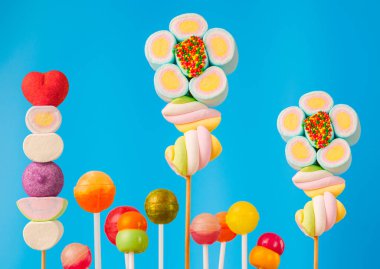 Çubukta çok renkli şekerler, mavi arkaplan. Mavi arka planda çok renkli lolipoplar (Chyupa-Chyup 'lar)