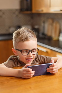 Çocuk, Avrupa 'nın gözlükleriyle yıllarca şarkı söylüyor. Telefonda konuşuyor. Çocuk, Avrupa 'nın gözlükleriyle yıllarca şarkı söylüyor. Mutfakta telefonla oynuyor.