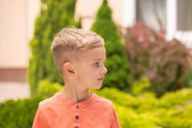 Beş yaşında bir çocuk surat yapıyor. Beş yaşında sarışın bir çocuk güneşli bir havada sokakta dikilirken surat asıyor..