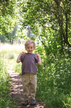 Kıvırcık saçlı bir çocuğun parkında yürüyüş. Hava güneşli, park çok renkli.