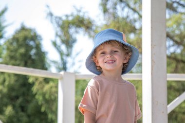 Kıvırcık saçlı bir çocuğun parkında yürüyüş. Hava güneşli, park çok renkli.