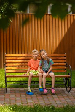 Kız ve erkek bir bankta oturuyor. Güneşli bir yaz gününde, beş yaşında bir oğlan ve bir kız bahçede bir bankta oturuyorlar..