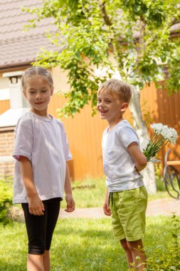 Altı yaşındaki bir oğlan bir kıza bir buket çiçek verir. Güneşli bir günde, bahçede oğlan kıza bir buket papatya verir..