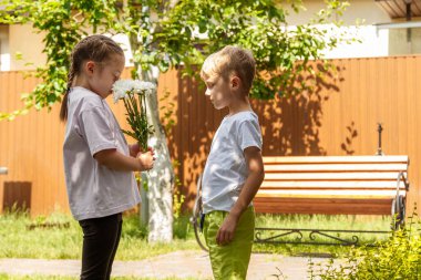 Altı yaşındaki bir oğlan bir kıza bir buket çiçek verir. Güneşli bir günde, bahçede oğlan kıza bir buket papatya verir..
