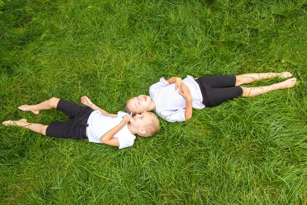Çocuklar çimlere uzanıp gökyüzüne bakarlar. Avrupa görünümlü altı yaşında bir erkek ve kız çocuğu yeşil gazın üzerinde farklı pozlarda yatıyor..