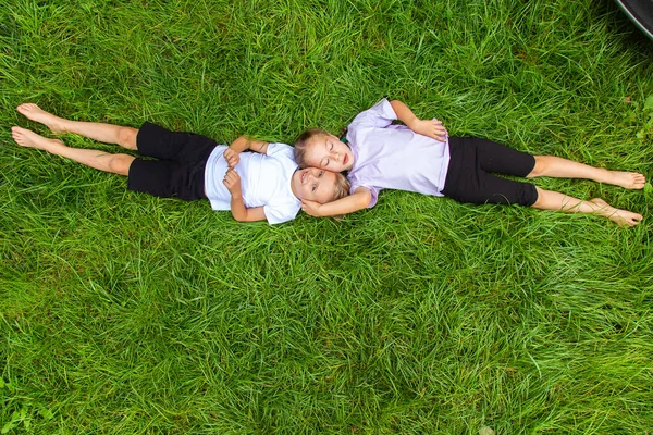 子供たちは芝生の上に横たわって空を見ています 6歳の男の子と女の子 ヨーロッパの外観は 異なるポーズで緑のガスに横たわっています — ストック写真