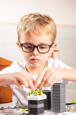 Altı yaşında (Avrupalı görünümlü) bir çocuk, tasarımcıyı masadan alır. Çocuk, yerçekimi elementleri olan bir müteahhit tarafından canlandırılır..