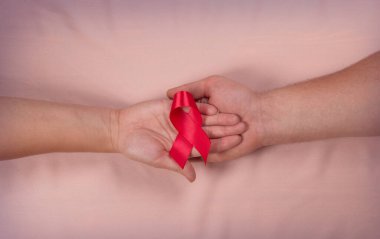 Erkek ve kadın ellerinde kırmızı kurdele HIV farkındalığı konsepti dünya kanser günü AIDS günü hipertansiyon günü