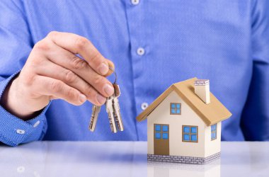 İş adamı, ev kredisini ve sigorta konseptini ipotek onayı için model ev anahtarları veriyor.