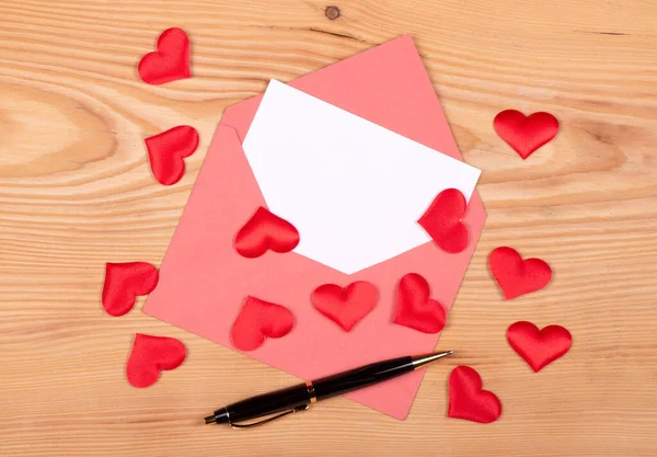 love letter Old envelope with lots of different red hearts over the wooden background