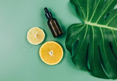 Büyük yeşil yapraklar, yeşil arka planda yüz masajı silindiri. Tropik palmiye yaprağı su damlalarıyla kaplanır. Yaz şablonu, düz yatış. Kozmetik ürünleri, cilt bakımı, sağlık