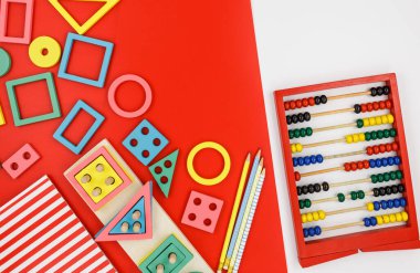 Kırmızı arka planda çok renkli ahşap bloklar. Moda bulmaca oyuncakları. Geometrik şekiller: kare, daire, üçgen, dikdörtgen. Anaokulu, anaokulu ya da kreş için eğitici oyuncaklar. Okula geri dön.