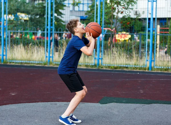 파란색 티셔츠를 귀엽게 놀이터에서 농구를 활동적 청소년 오렌지 가지고 경기를 — 스톡 사진