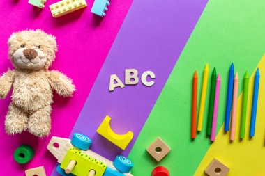 Tahta tuğlalar, tren, kalemler, macenta yeşil arka planda oyuncak ayı. Çocuklar için tahta oyuncaklar ve anaokulu eğitimi