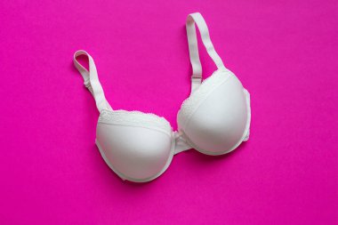 Pembe arka planda beyaz sütyen. Sütyen, mor arka planda dantel iç çamaşırı. Güzellik blogu konsepti. Üst manzara, düz uzanma 